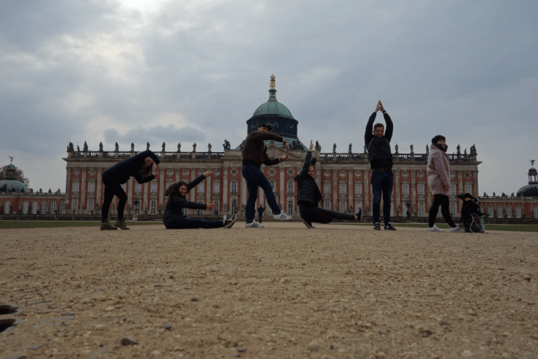 Das Bild zeigt eine Gruppe Menschen, die mit ihren Körpern den Schriftzug Berlin formen vor dem Palais Potsdam in Berlin.