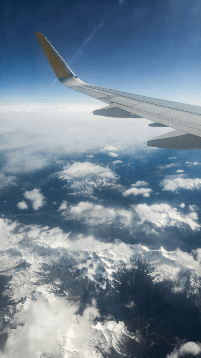 Das Bild wurde aus dem Flugzeug aufgenommen und zeigt Wolken und die Altpen von oben.