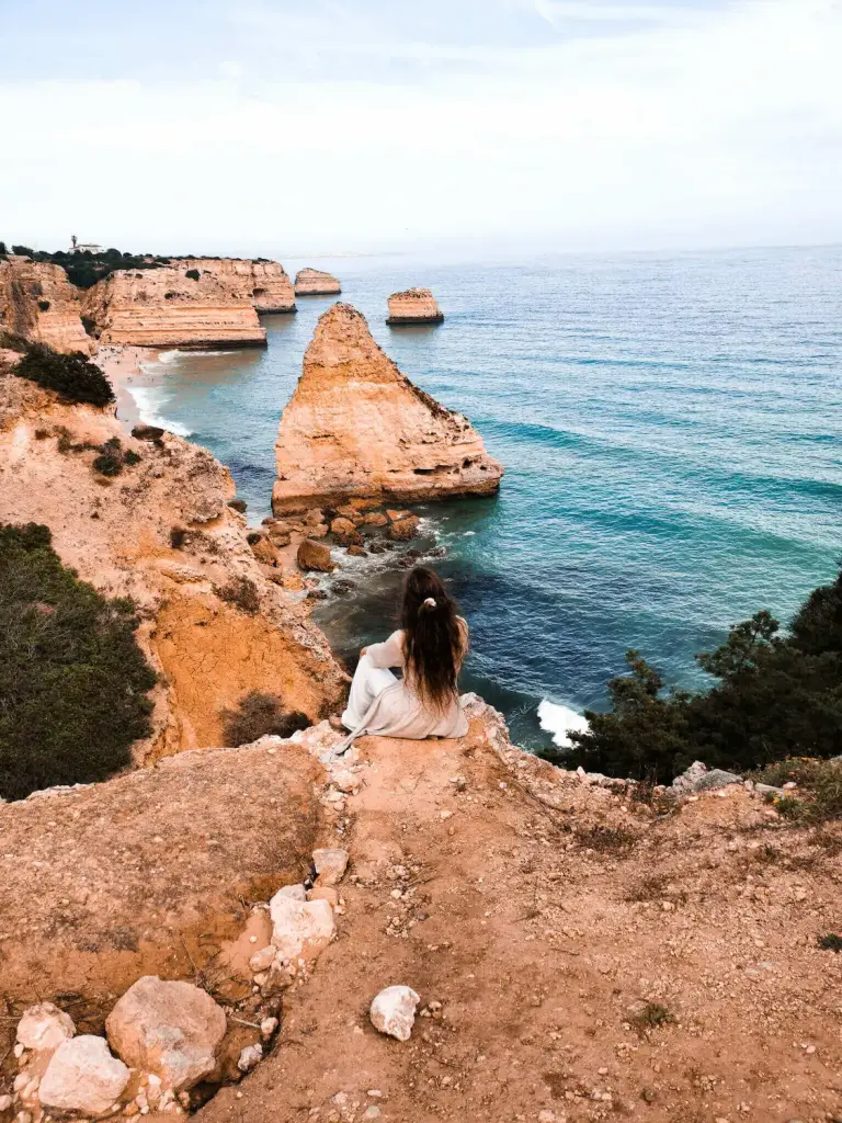 Laura von @einfach.herumgurken sitzend an der Klippe der Algarve in Portugal