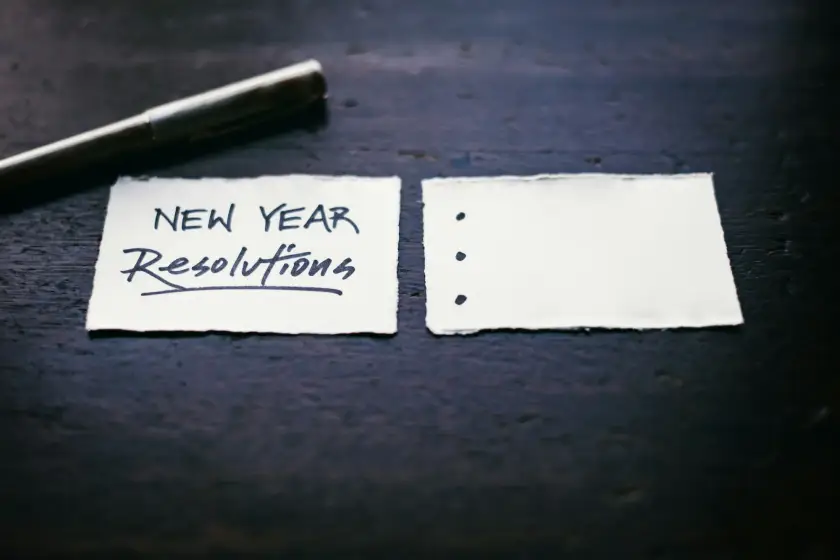 Neujahrsvorsätze, Vorsätze, die zum Teil unrealistisch sind und nur schwer eingehalten werden können. Das Bild zeigt eine Zettel der die Worte "new years reslutions" trägt.