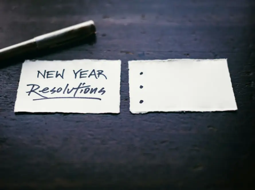 Neujahrsvorsätze, Vorsätze, die zum Teil unrealistisch sind und nur schwer eingehalten werden können. Das Bild zeigt eine Zettel der die Worte "new years reslutions" trägt.