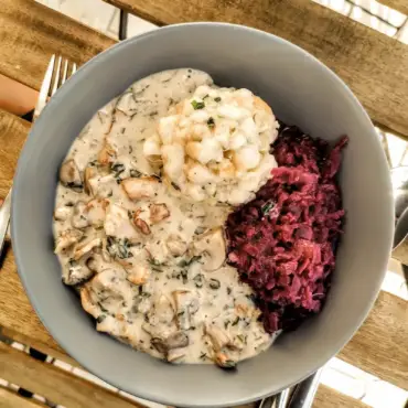 Das Bild zeigt ein Teller mit veganer Eierschwammerlsoße, Blaukraut und Semmelknödel. Ein typisch österreichisches Herbstgericht von einfach-herumgurken.