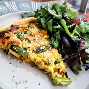 Das Bild zeigt ein Stück einer veganen Quiche mit Spargel und Räuchertofu von einfach-herumgurken.