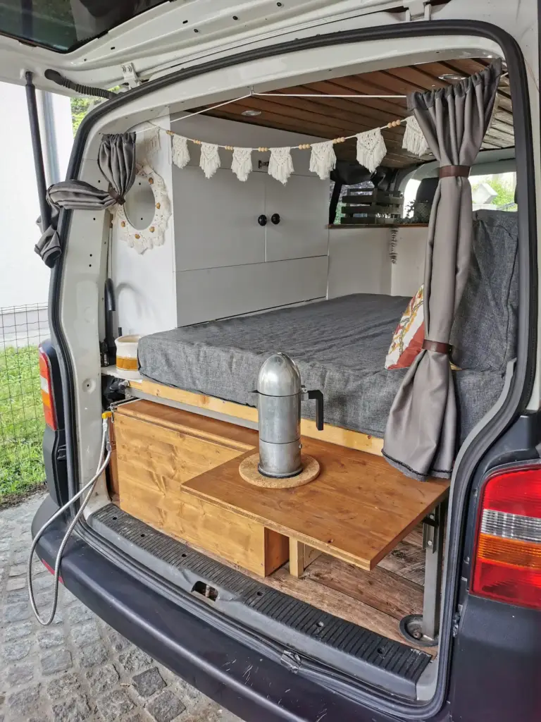 Vanausbau: fertiger Innenausbau - Ansicht von hinten auf das Bett, Regal und die Küche mit ausgeklapptem Brett.
