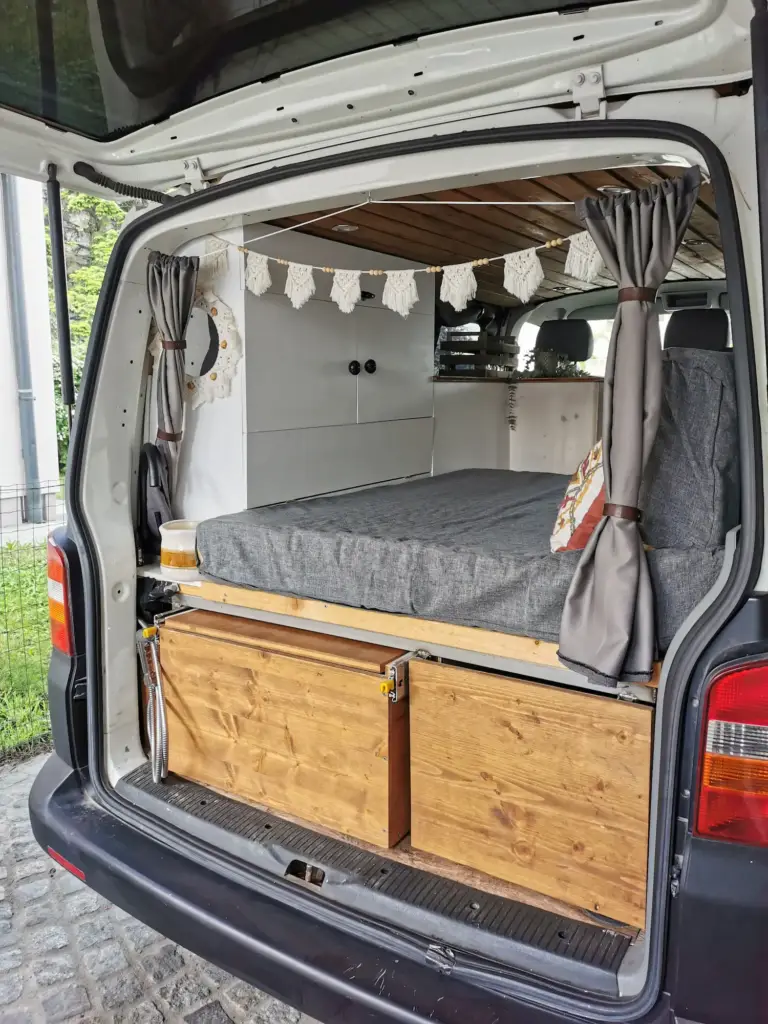 Vanausbau: fertiger Innenausbau - Ansicht von hinten auf das Bett, Regal und die Küche.