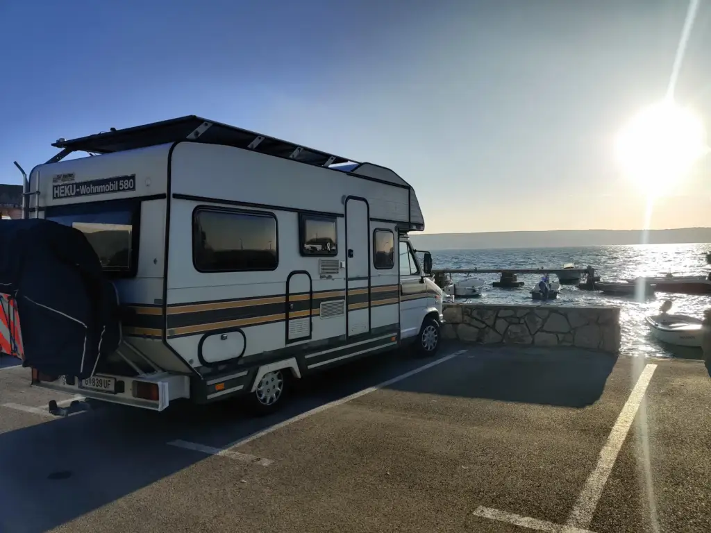 Das Wohnmobil Gerti von einfach-herumgurken im Hafen. Im Hintergrund sieht man das Meer, die Insel Krk und die untergehende Sonne.